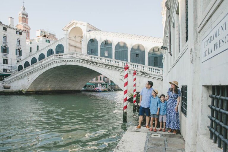 Find out where to book affordable Venice photographers with tips by top family travel blog Marcie in Mommyland. Image of a family by the Rialto Bridge in Venice