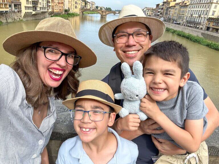 Find out how to spend 2 days in Florence with kids by top family travel blog Marcie in Mommyland! Image of a family selfie in Florence with the Arno river in the background