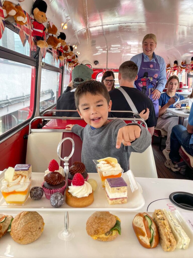 Image of a boy having afternoon tea on a vintage double decker bus in London