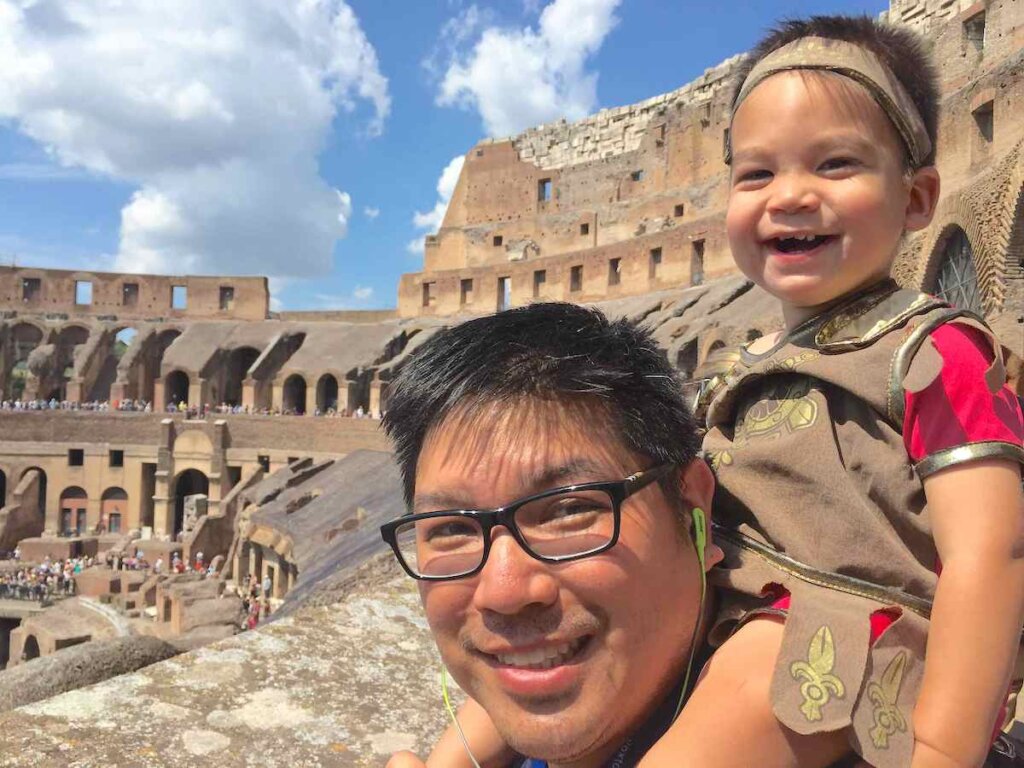 Image of a dad with a toddler on his shoulders at the Colosseum in Rome