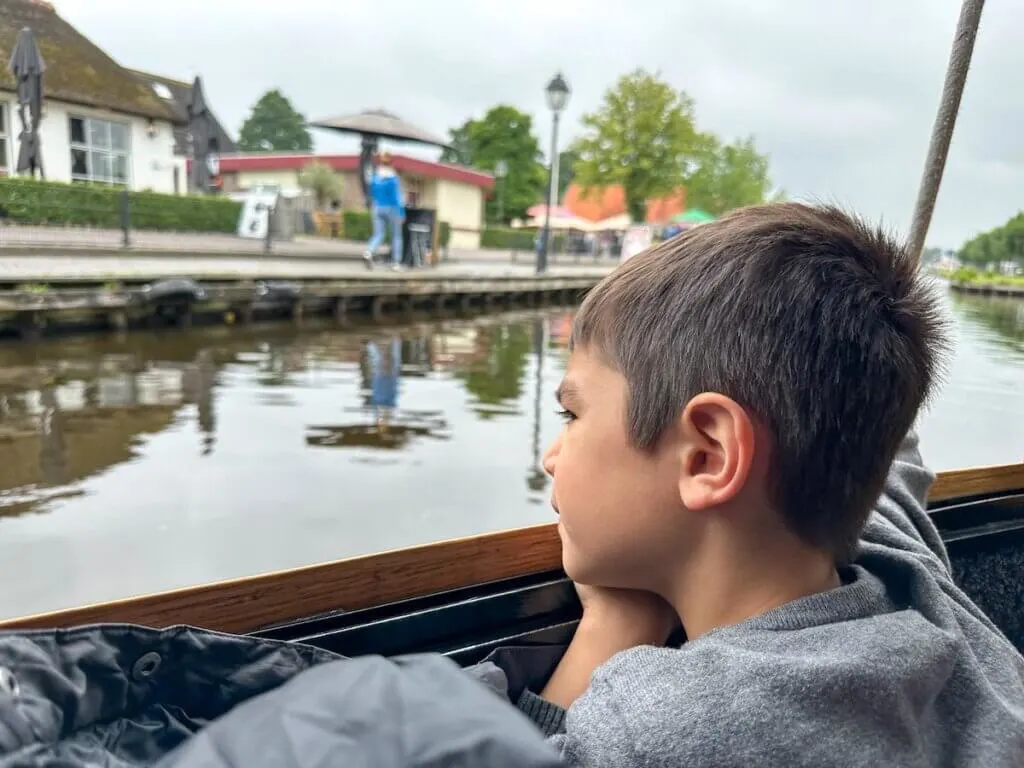 Image of a boy looking out from a canal boat in Giethoorn Netherlands