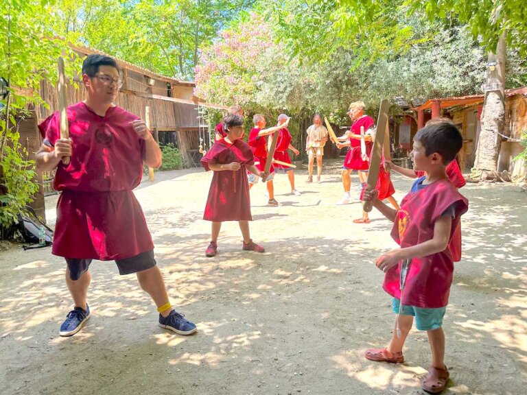Find out how to become a gladiator for a day in Rome Italy with tips by top family travel blog Marcie in Mommyland. Image of a kids and adults at the Rome Gladiator School