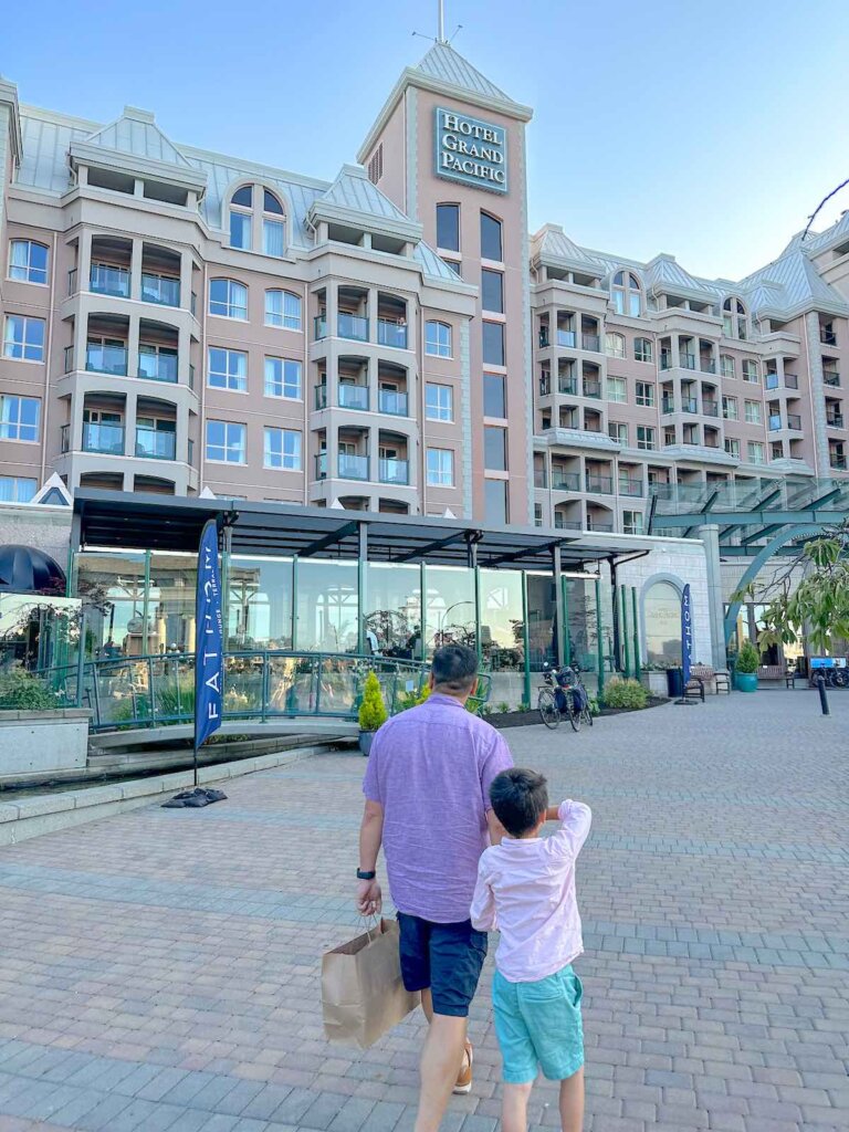Image of a dad and son walking in front of the Hotel Grand Pacific in Victoria BC