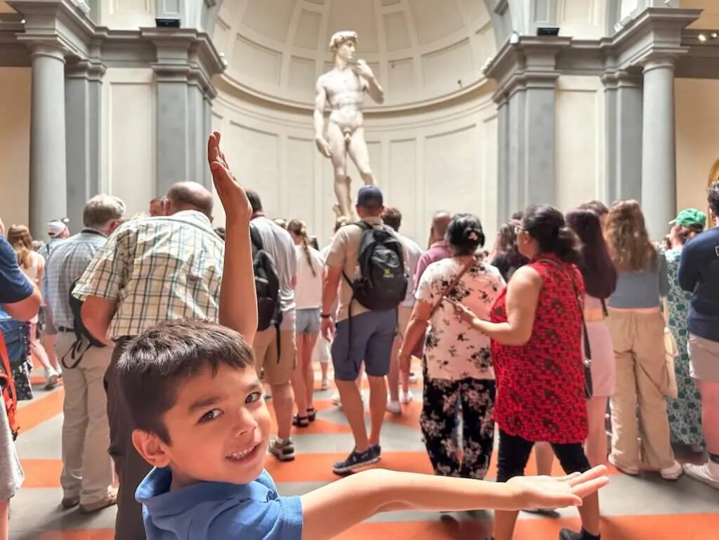 Image of a boy in front of Michelangelo's David statue