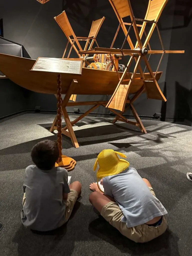 Image of two boys sketching a wooden machine at the Da Vinci Museum in Florence Italy