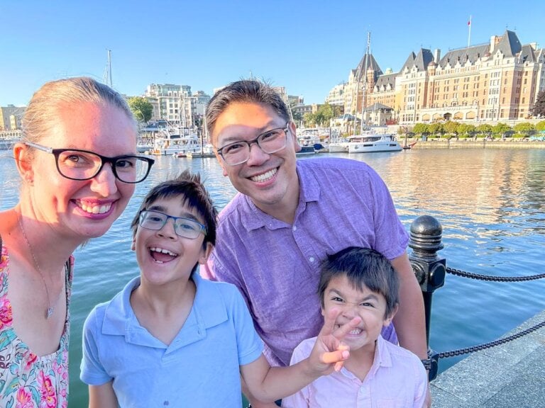 Find out how to spend the weekend in Victoria BC with kids with tips by top family travel blog Marcie in Mommyland. Image of a family in front of the Inner Harbour