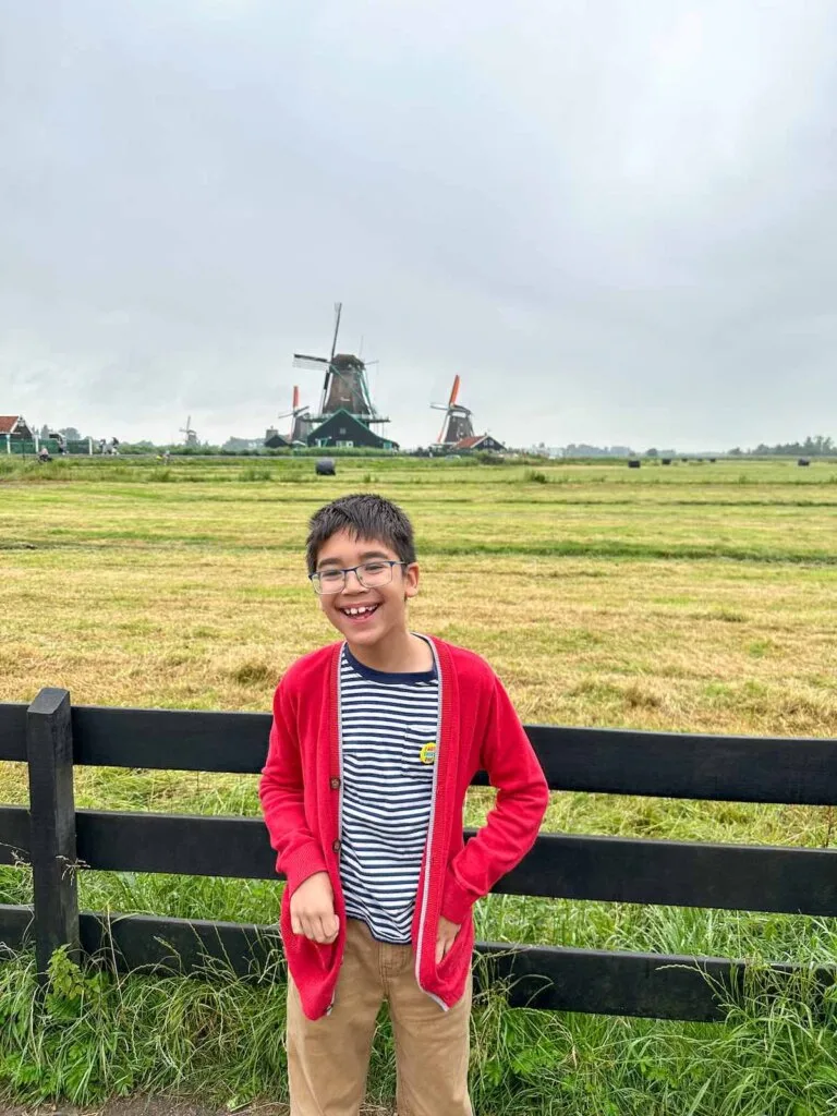 Image of a boy laughing in front of a Zaanse Schans windmill