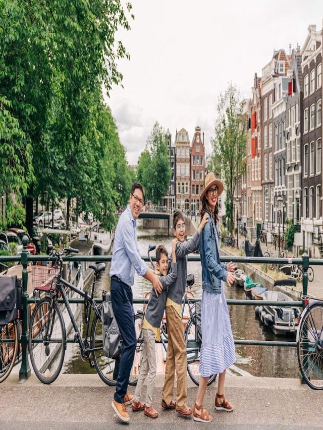 Find out how to plan a trip to Europe with kids with tips by top family travel blog Marcie in Mommyland. Image of a family doing a conga line on a bridge in Amsterdam