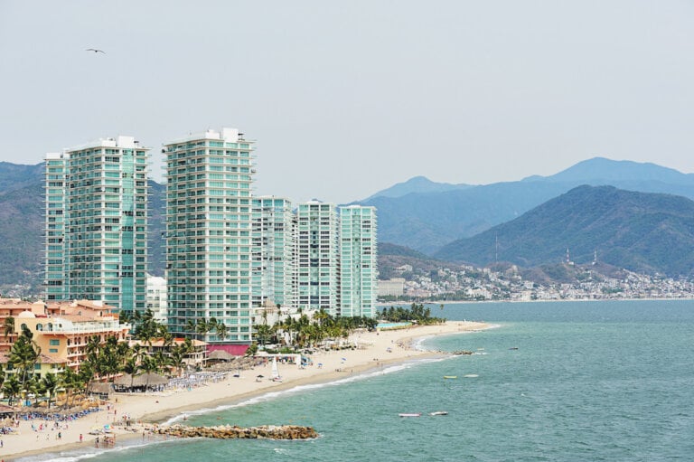 Find out the Best All Inclusive Resorts in Puerto Vallarta for Families according to top family travel blog Marcie in Mommyland. Image of tall hotels and the beach in Puerto Vallarta Mexico
