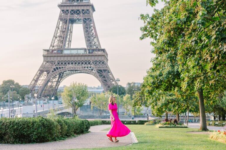 Find out how to plan a trip to Paris by top travel blog Marcie in Mommyland. Image of a woman in a pink dress in front of the Eiffel Tower