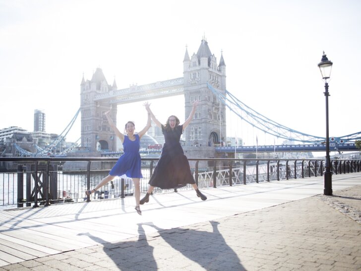 Find out what to do in London in a day with tips from top family travel blog Marcie in Mommyland. Image of two woman jumping in front of Tower Bridge