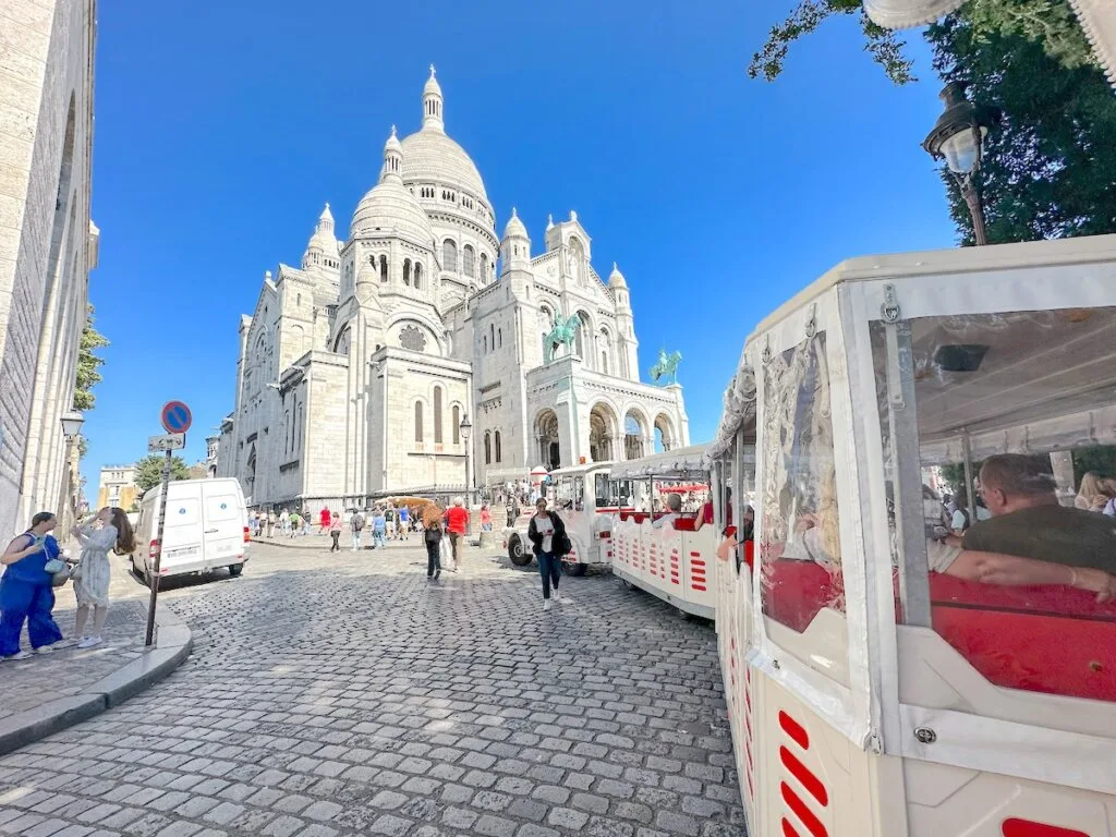 Image of a little white train in front of Sacre Coeur in Paris