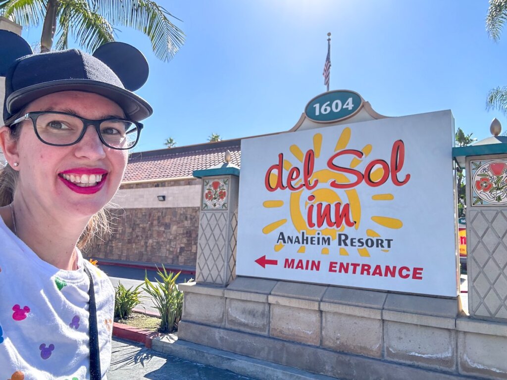 Image of Disney blogger Marcie Cheung next to the Del Sol Inn sign at one of the Best Disneyland Hotels Within Walking Distance