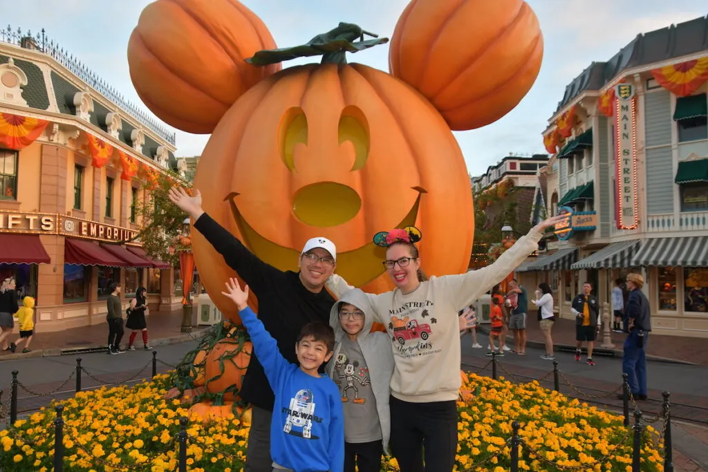 Image of Marcie Cheung of Marcie in Mommyland and her family in front of the big Mickey pumpkin at Disneyland