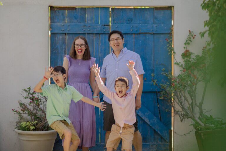 Find out whether families should stay in San Jose del Cabo vs Cabo San Lucas with tips from top family travel blog Marcie in Mommyland. Image of a family in front of a blue door in Los Cabos Mexico