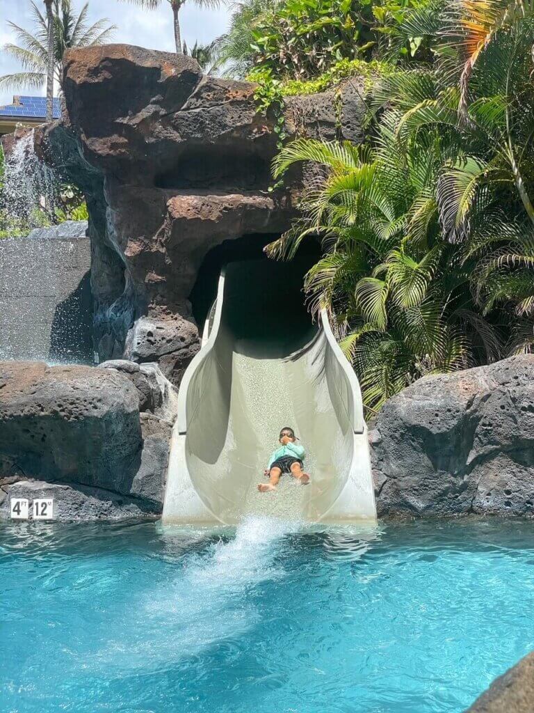 Image of a boy going down a water slide at Koloa Landing Resort. Photo credit: Marcie Cheung of Marcie in Mommyland