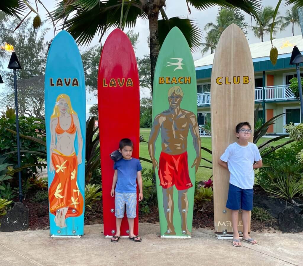 Image of two boys in front of surfboards that say Lava Lava Beach Club. Photo credit: Marcie Cheung of Marcie in Mommyland