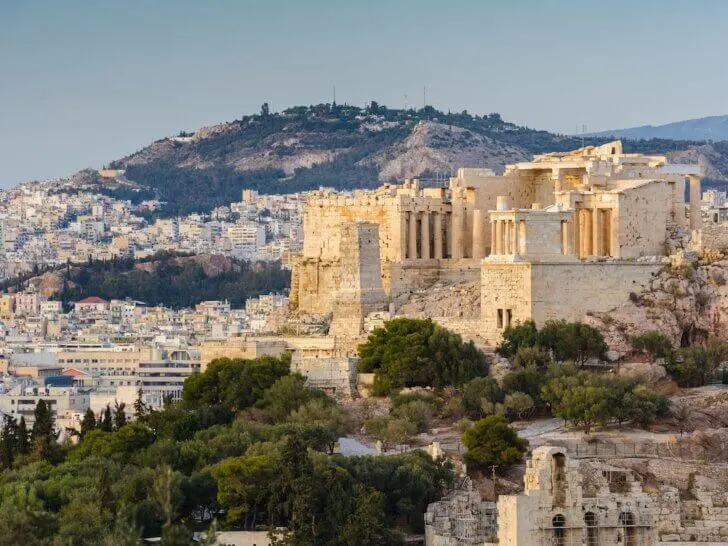 Check out the best Athens hotels for families recommended by top family travel blog Marcie in Mommyland. Image of Entrance to Ancient Acropolis in rays of sunset. Athens Greece