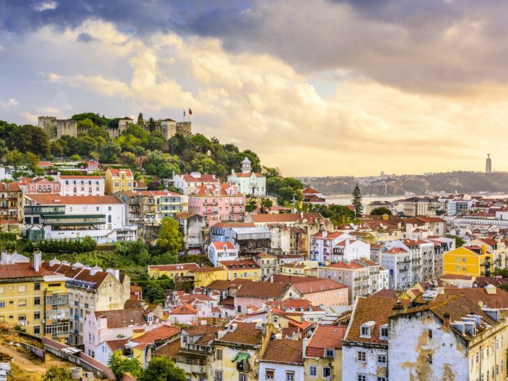 Check out the best Lisbon hotels for families recommended by top family travel blog Marcie in Mommyland. Image of Lisbon, Portugal skyline at Sao Jorge Castle at dusk.