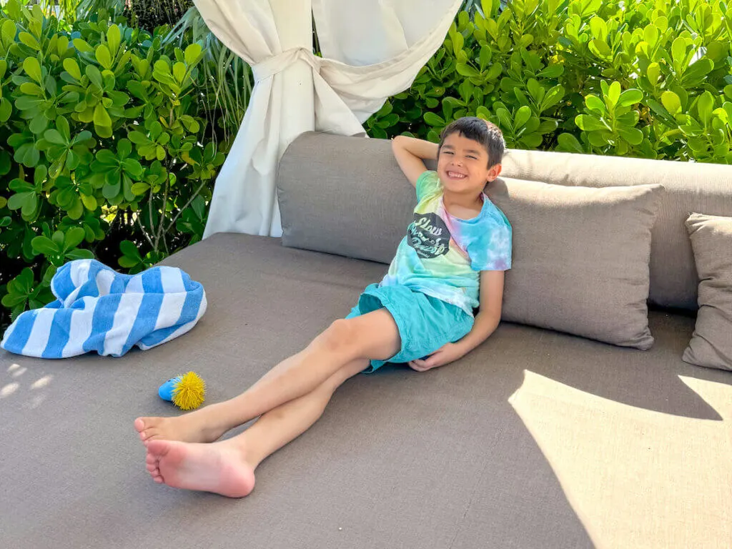 Find out the best kid-friendly Caribbean resorts for families recommended by top family travel blog Marcie in Mommyland. Image of a boy in a cabana in the Caribbean.