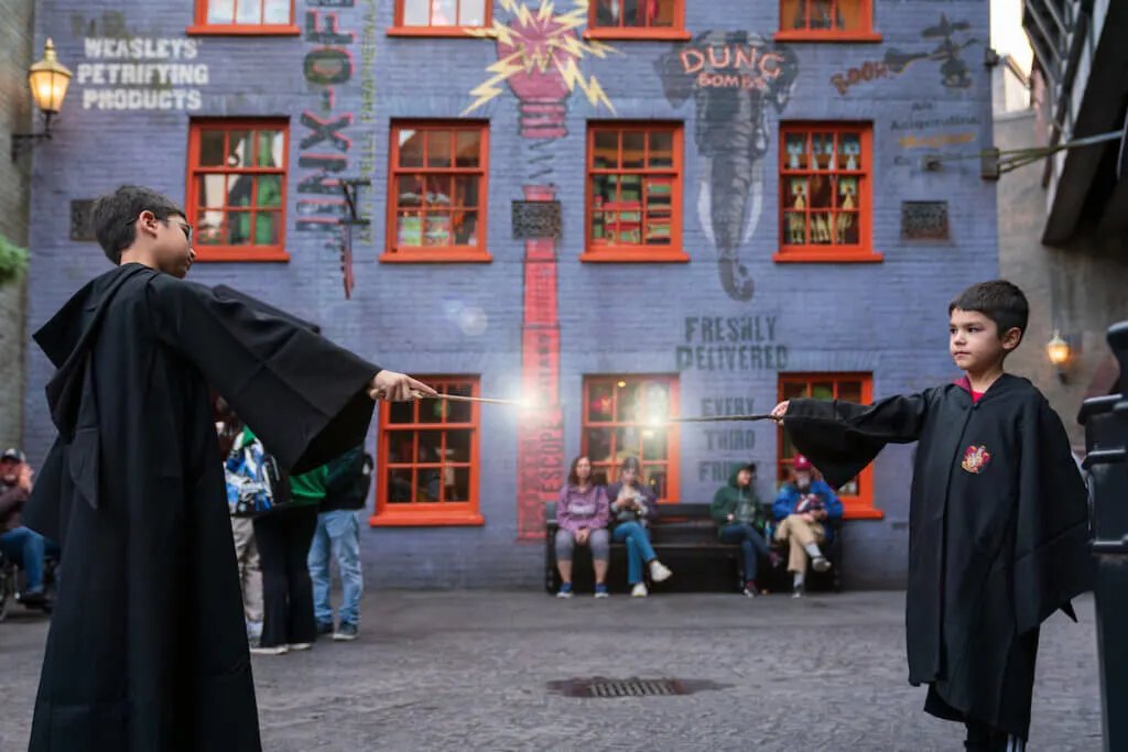 Image of two boys dressed in Hogwarts robes doing a wand battle at Diagon Alley in Universal Studios Florida. Photo credit: Sees the Day Photography