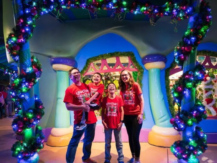 Find out whether or not it's worth visiting Universal Studios at Christmas with tips by top family travel blog Marcie in Mommyland. Image of Marcie Cheung and her family posing with Christmas lights at Grinchmas at Universal Studios Orlando. Photo credit: Sees the Day Photography