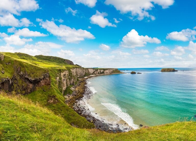 Check out these tips for visiting Ireland in summer by top family travel blog Marcie in Mommyland. Image of Carrick-a-Rede, Causeway Coast Route in a beautiful summer day, Northern Ireland, United Kingdom
