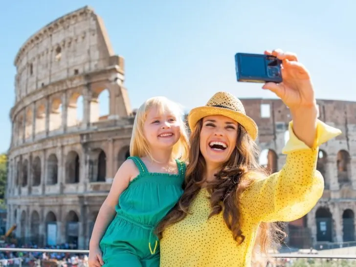 Check out the top tips for visiting Italy with a toddler by top family travel blog Marcie in Mommyland. Image of a mom and toddler taking a selfie in front of the Colosseum.