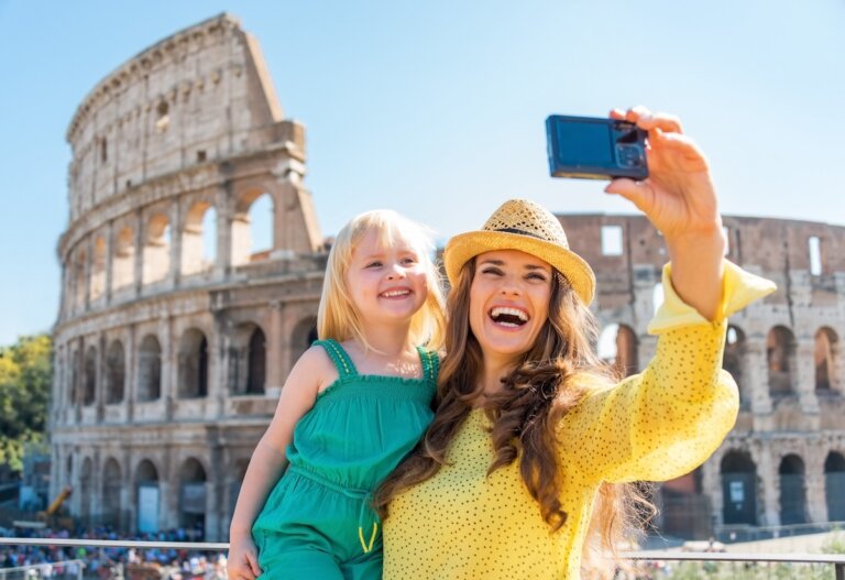 Check out the top tips for visiting Italy with a toddler by top family travel blog Marcie in Mommyland. Image of a mom and toddler taking a selfie in front of the Colosseum.