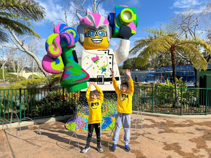 Check out these top tips for visiting LEGOLAND on a budget by top family travel blog Marcie in Mommyland. Image of two boys posing with a giant LEGO minifigure at LEGOLAND California