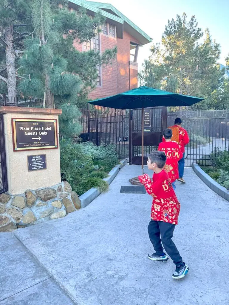 Image of a dad and two boys using the private DCA entrance from Pixar Place Hotel.