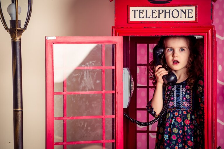 Check out the best things to do in London with a toddler recommended by top family travel blog Marcie in Mommyland. Image of a little girl hides and plays in a traditional red telephone booth