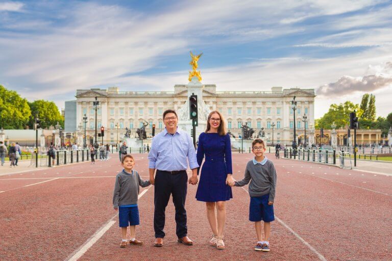 Get this checklist for traveling abroad with kids by top family travel blog Marcie in Mommyland. Image of Marcie Cheung and her family in front of Buckingham Palace in London