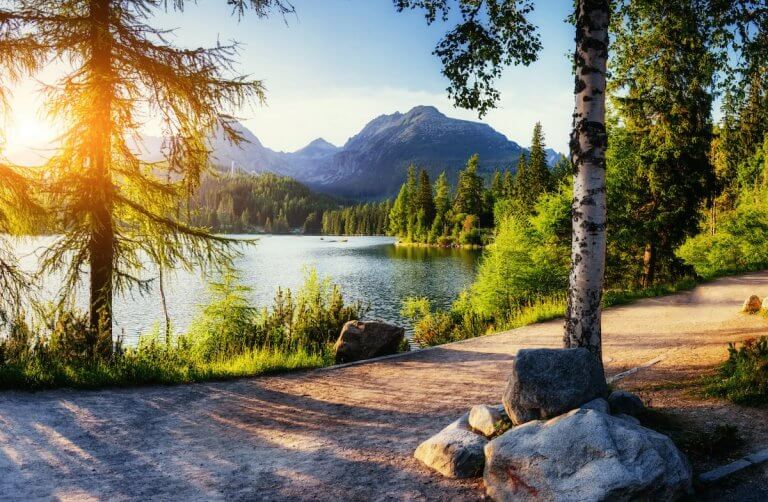 Find out how to save money on summer travel with tips from top family travel blog Marcie in Mommyland. Image of Majestic mountain lake in National Park High Tatra. Strbske ples