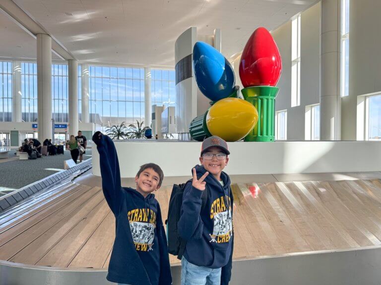Find out the best family travel tips from top family travel blog Marcie in Mommyland. Image of two boys at an airport during Christmas