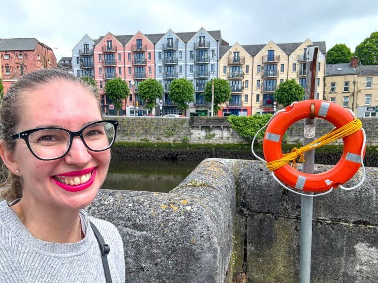 Find out the best things to do in Cork with kids by top family travel blog Marcie in Mommyland. Image of Marcie Cheung in front of colorful houses in Cork Ireland