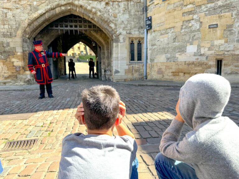Find out whether or not it's worth visiting the Tower of London with kids with tips from top family travel blog Marcie in Mommyland. Image of two boys watching the Opening Ceremony at the Tower of London