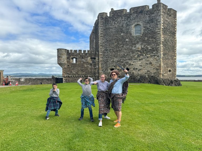 Find out how to spend 10 days in Scotland with Kids with tips from top family travel blog Marcie in Mommyland. Image of Marcie Cheung and her family in front of Blackness Castle in Scotland