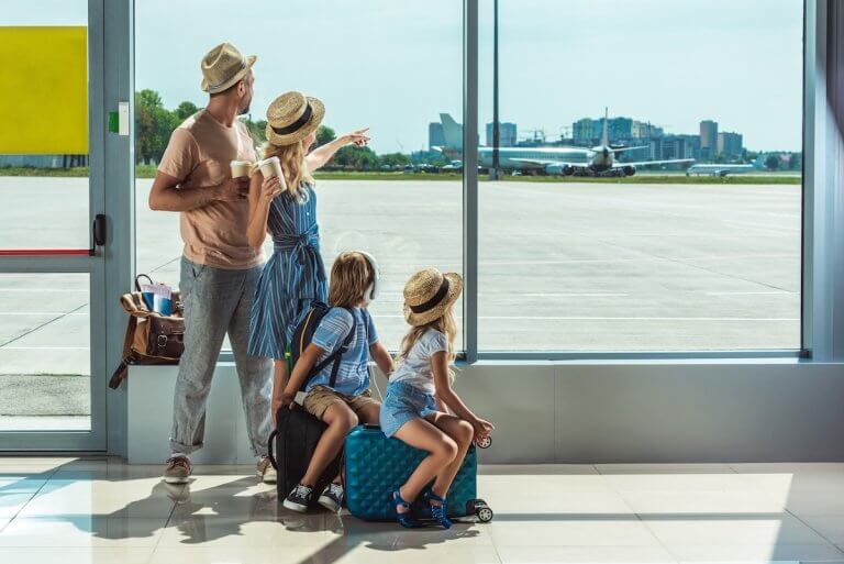 Find out how to save money on family travel during summer or fall with tips from top family travel blog Marcie in Mommyland. Image of a family at the airport