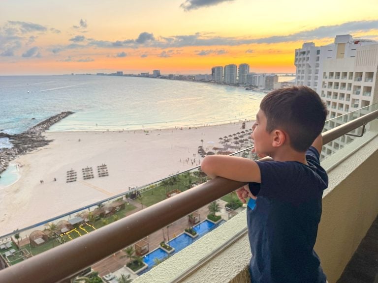 Check out this honest Hyatt Ziva Cancun review by top family travel blog Marcie in Mommyland. Image of a boy overlooking the Hyatt Ziva Cancun beach area