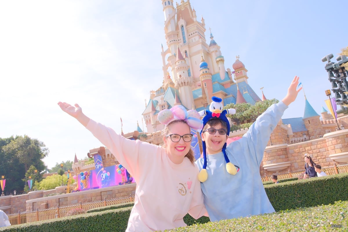Find out how to spend 1 day at Hong Kong Disneyland. Image of Marcie Cheung and her son at Hong Kong Disneyland in front of the castle.